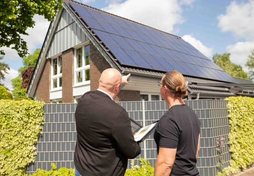 Beratungsgespräch vor einem Dach mit Solar-PV Modulen 