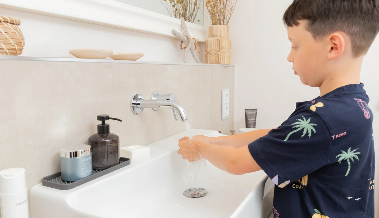 Junge wäscht die Hände mit Wasser