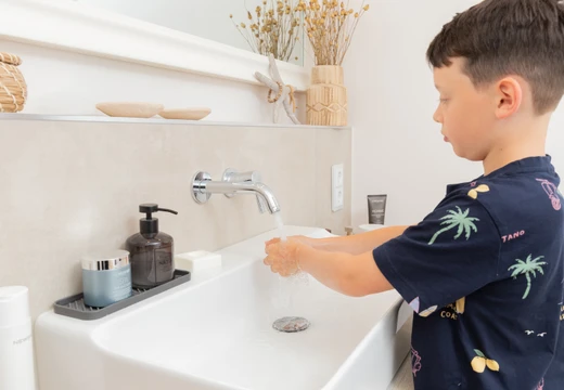 Junge wäscht die Hände mit Wasser
