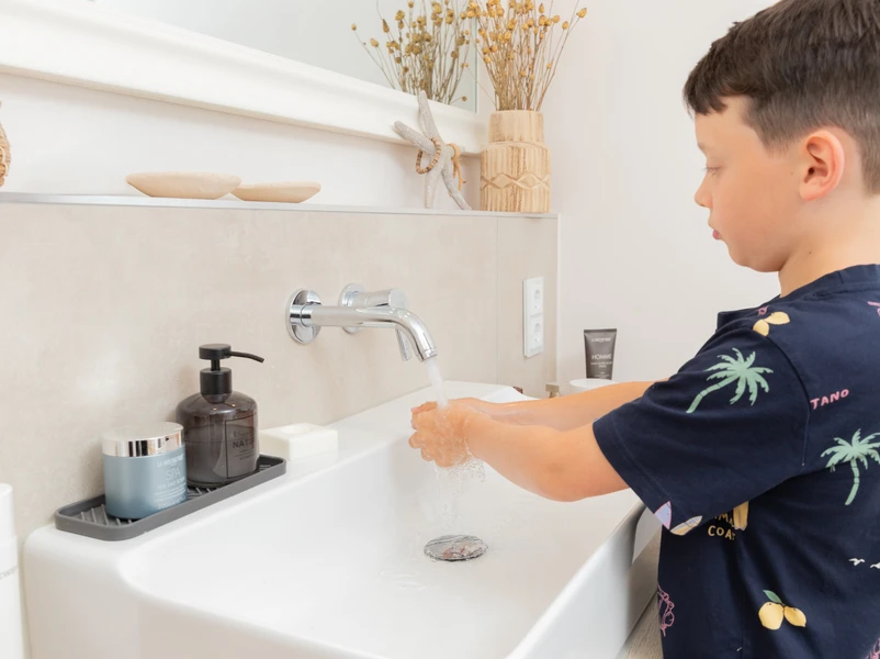 Junge wäscht die Hände mit Wasser